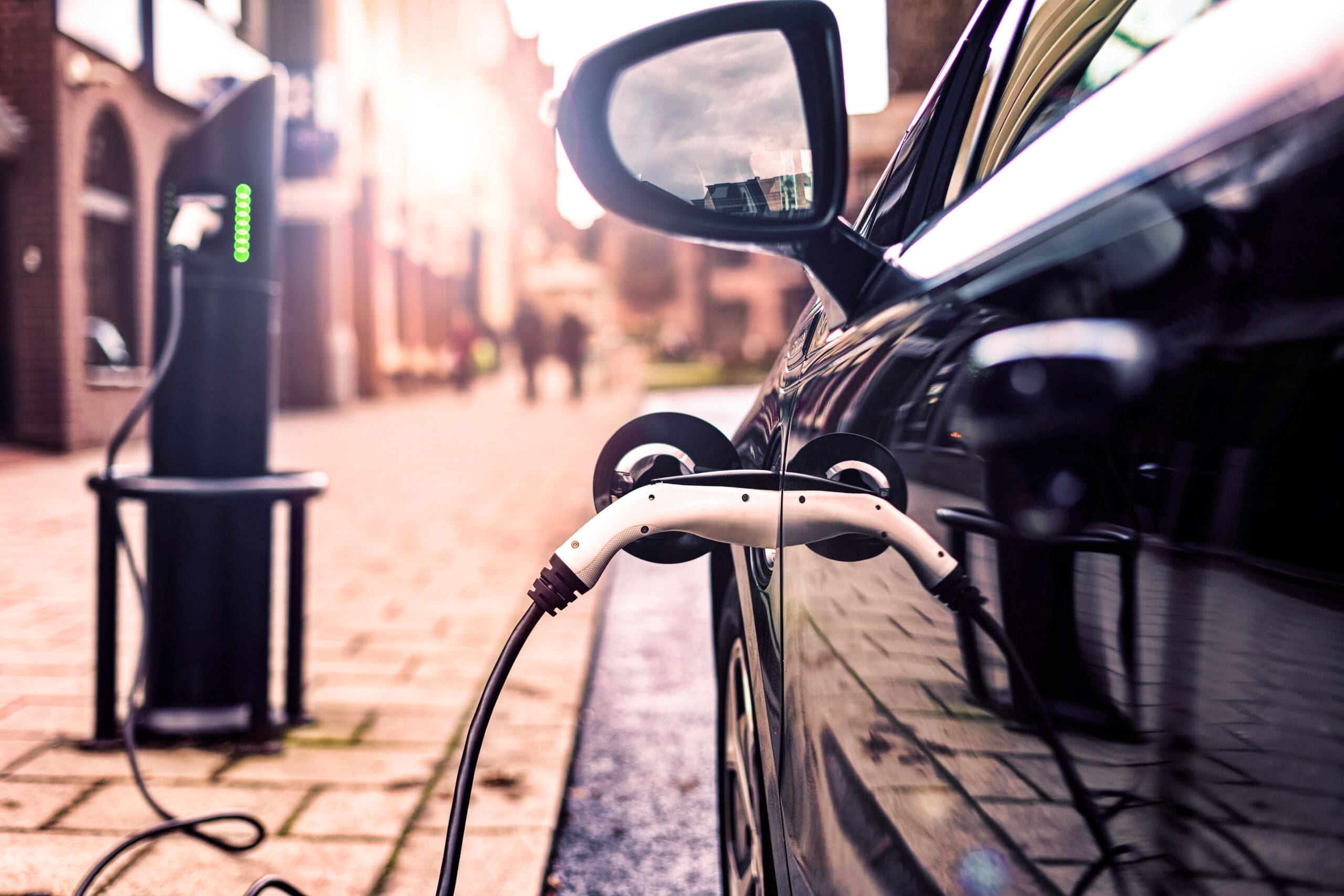 Close-up of an EV car plugged into a charger on the street side.